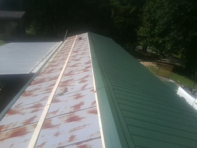 Old rusted panels beside newly installed green metal roofing — Wind Damage Roof Repair by Roofing Brothers in Palm Harbor