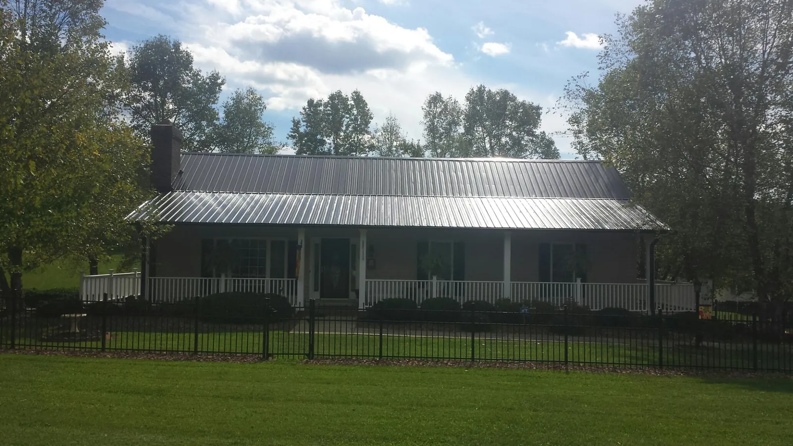 Gray metal roof on a brick ranch with a full width front porch — Gutter Guard Installation work by our crew in Palm Harbor