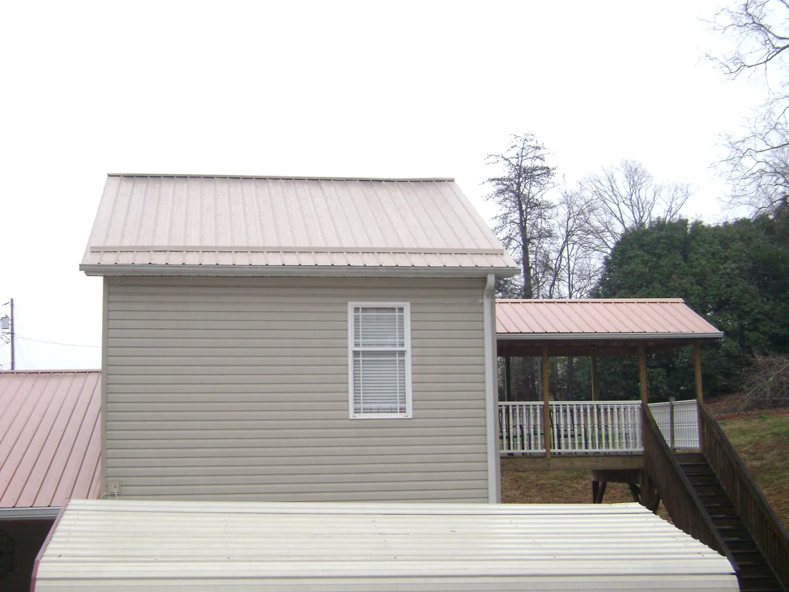 Tan metal roofs on a two story addition and attached porch, from a Roof Replacement job in Palm Harbor