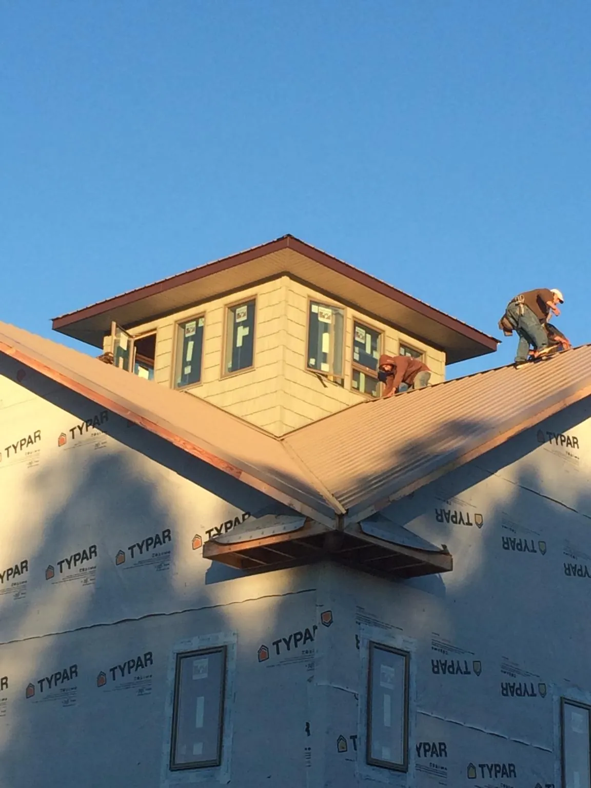 Roofers working around a rooftop cupola on a new metal roof at sunset — Roof Waterproofing in Palm Harbor by Roofing Brothers